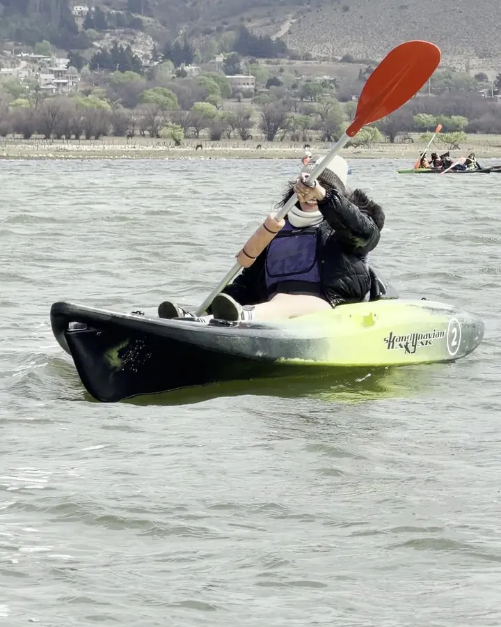 Una chica rema en kayak en un lago.